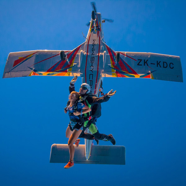 Skok w tandemie o zachodzie słońca z oświetlonym samolotem PAC 750 XSTOL. Tandem pilotem jest Krzysiek.